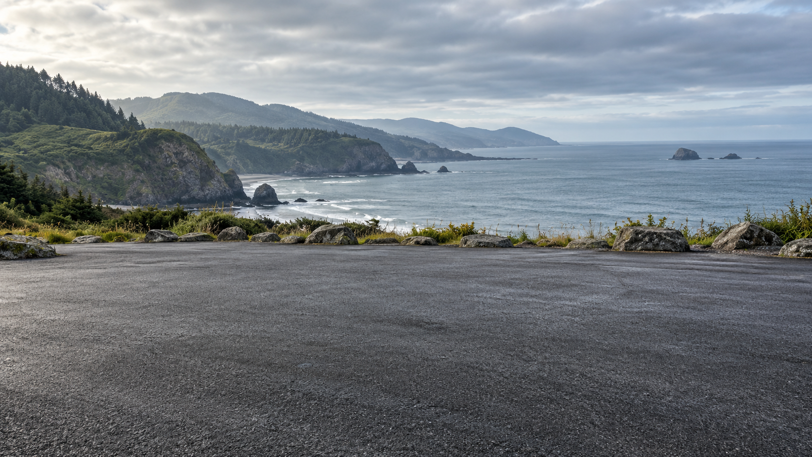 Empty coastal asphalt turnout with a blue-grey sea and soft overcast light