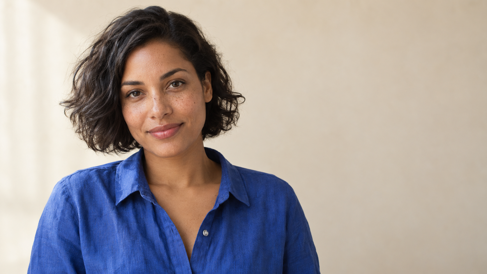 Original fictional woman with natural freckles short wavy black hair and a cobalt shirt