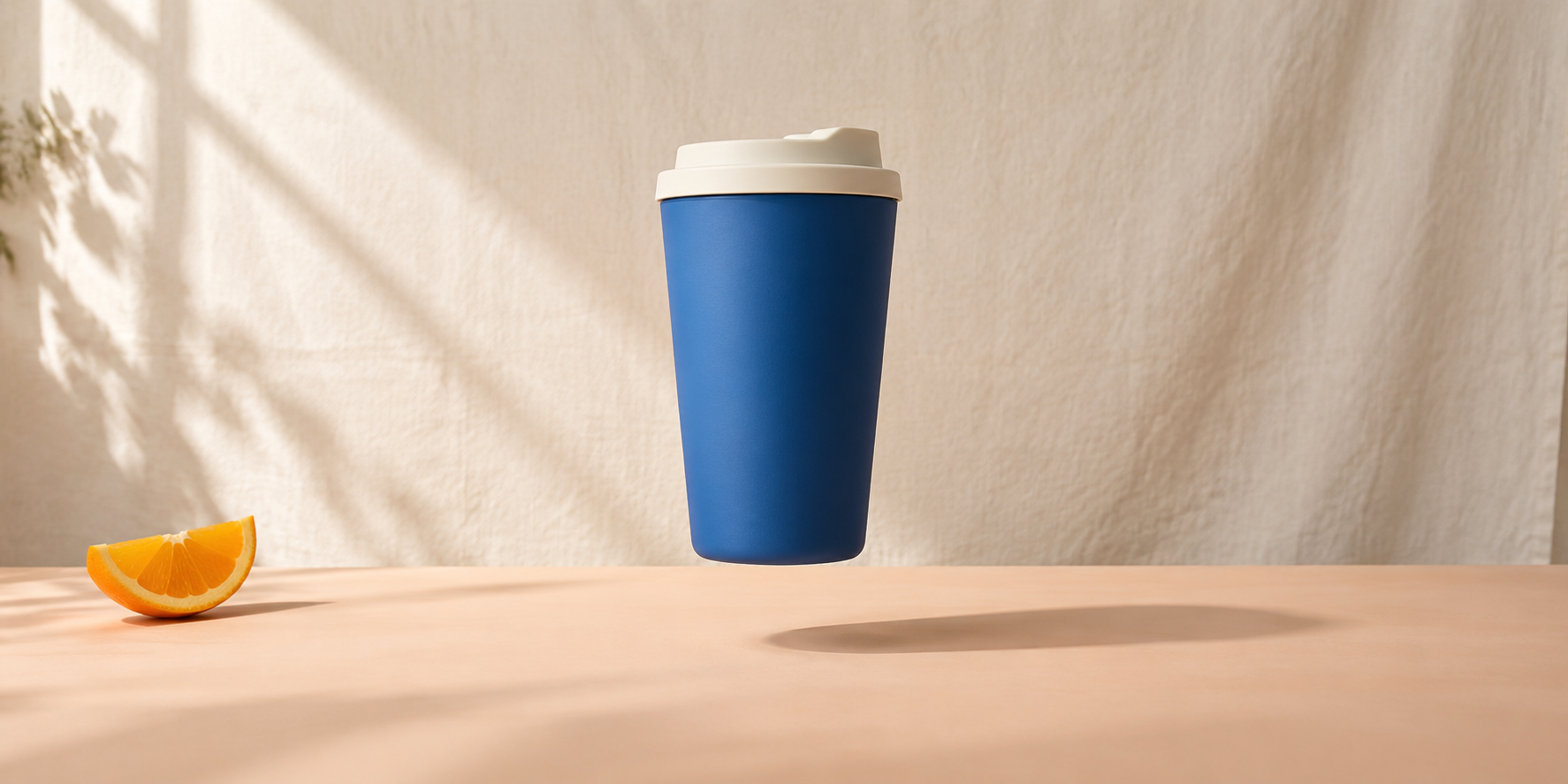 Original generated cobalt travel cup hovering above a peach tabletop with a separate cast shadow